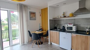 Cocina moderna con lavavajillas, microondas y fregadero. Hay una zona de comedor con una mesa y sillas.