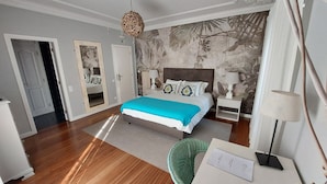 Un dormitorio moderno con una cama grande, suelo de madera y un mural decorativo en la pared.