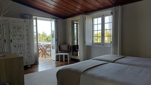 Un dormitorio con dos camas, techo de madera, un armario, una mesita y vistas al exterior.