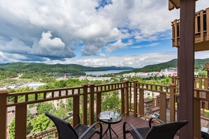 A balcony with a table and chairs, overlooking a scenic view of a lake and surrounding buildings. - L'Altitude - RVMT (Mont-Tremblant)