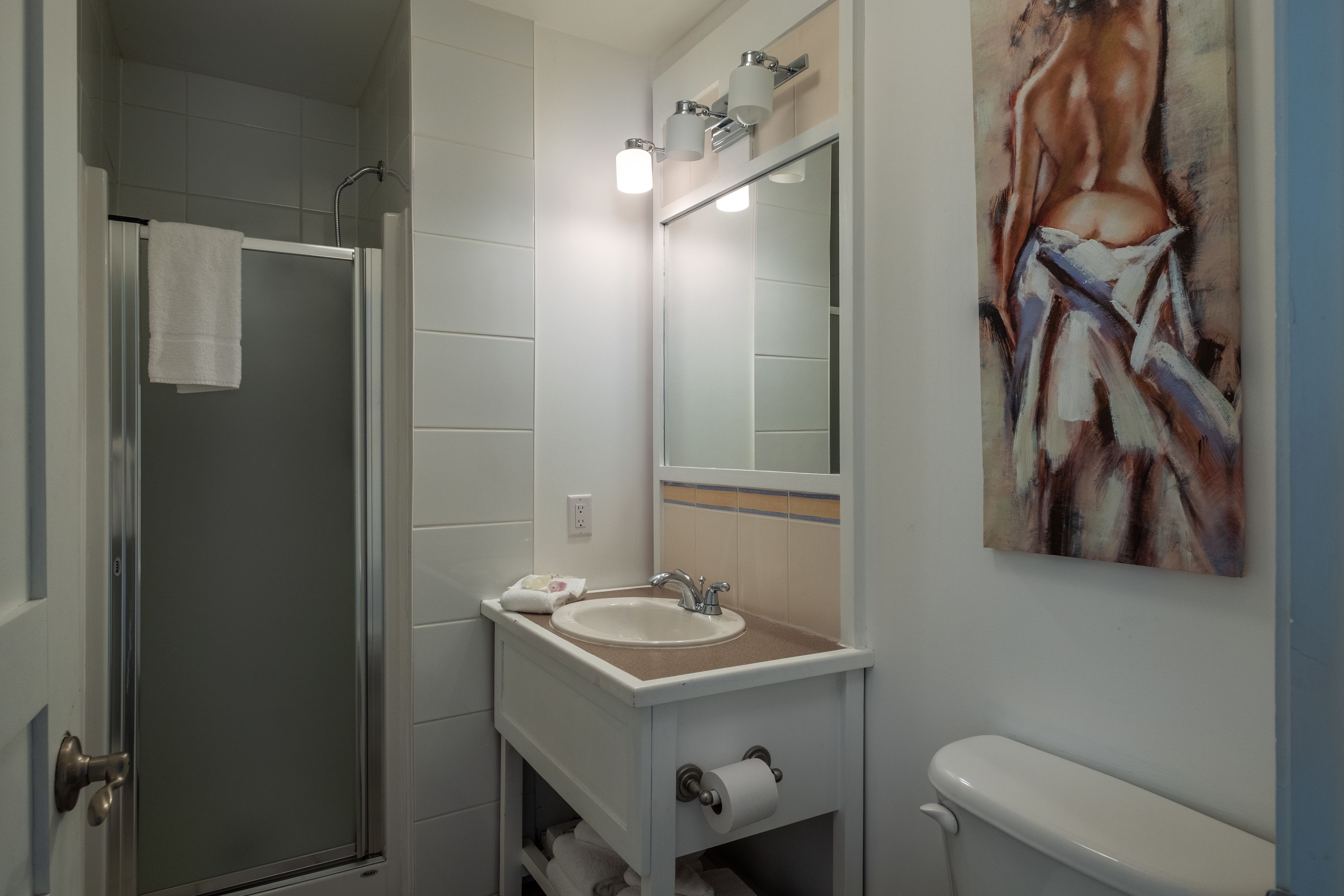 Une salle de bain avec une douche à parois de verre, un lavabo avec un miroir au-dessus et des toilettes.