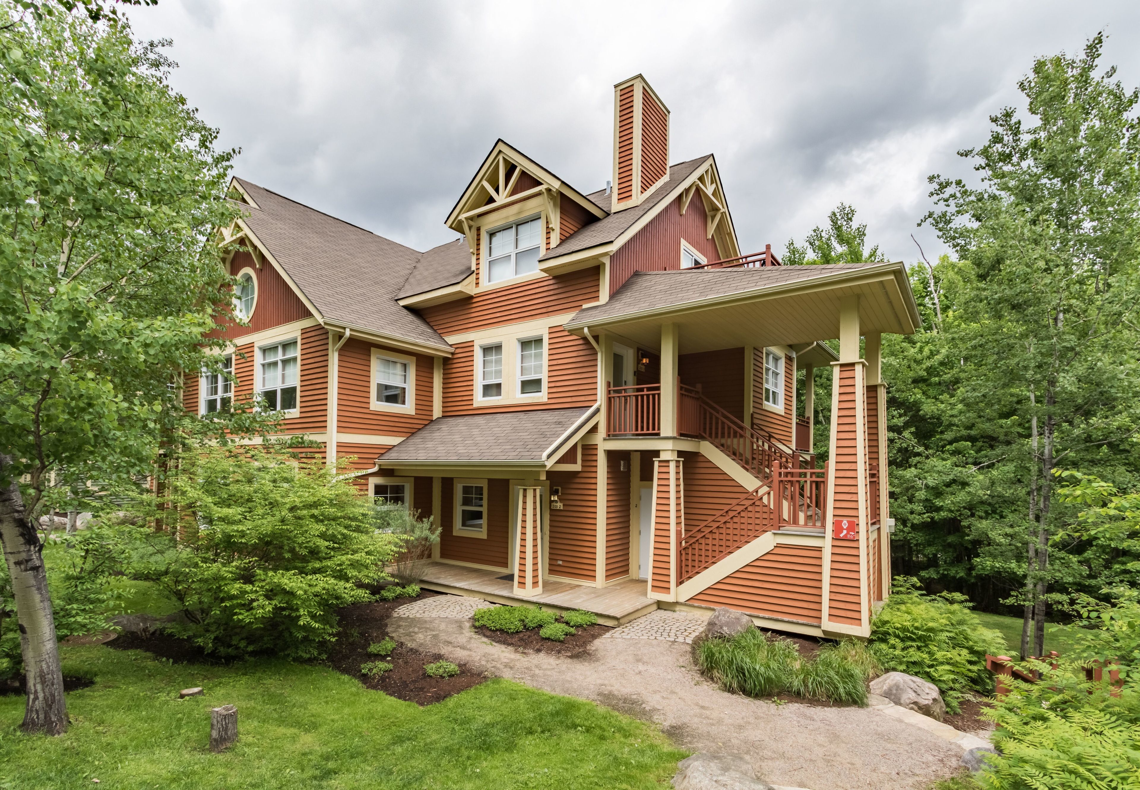 A large, two-story house with a prominent front porch, multiple windows, and a chimney.