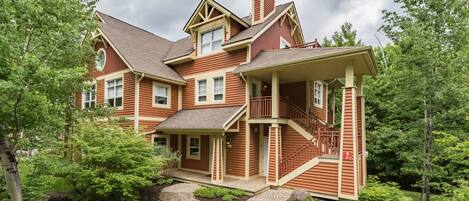 A large, two-story house with a prominent front porch, multiple windows, and a chimney.