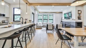 Una cucina moderna con isola centrale, sgabelli da bar e zona pranzo con tavolo e sedie in legno.