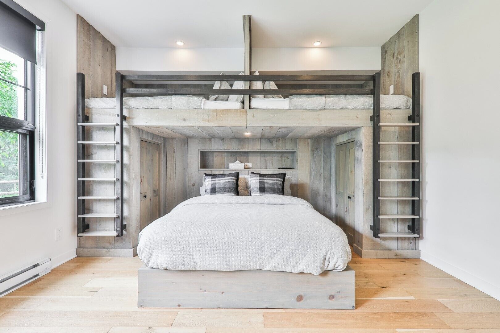 Une chambre avec un lit superposé, des murs en bois et une fenêtre.