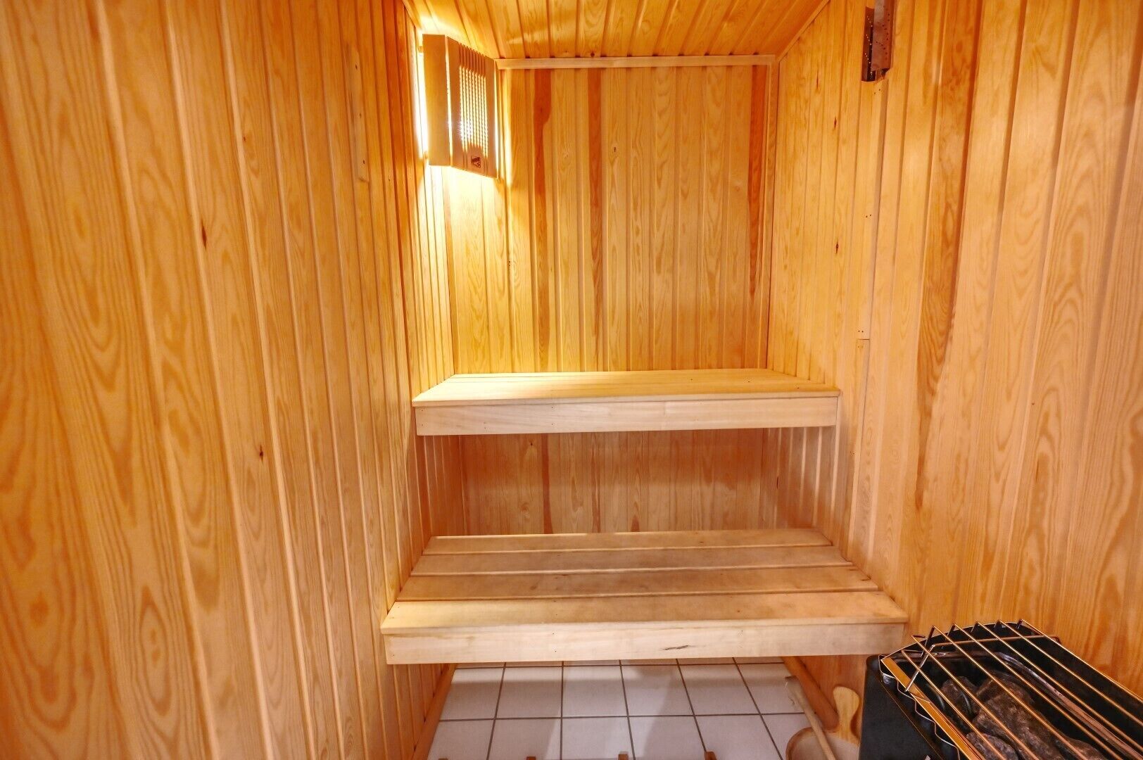 A wooden sauna with two benches and a tiled floor.