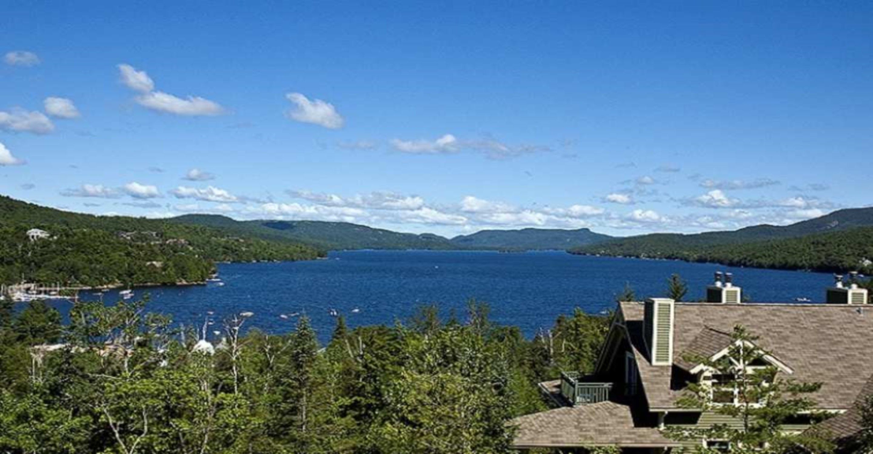 A lakeside view with a house in the foreground and boats on the water.