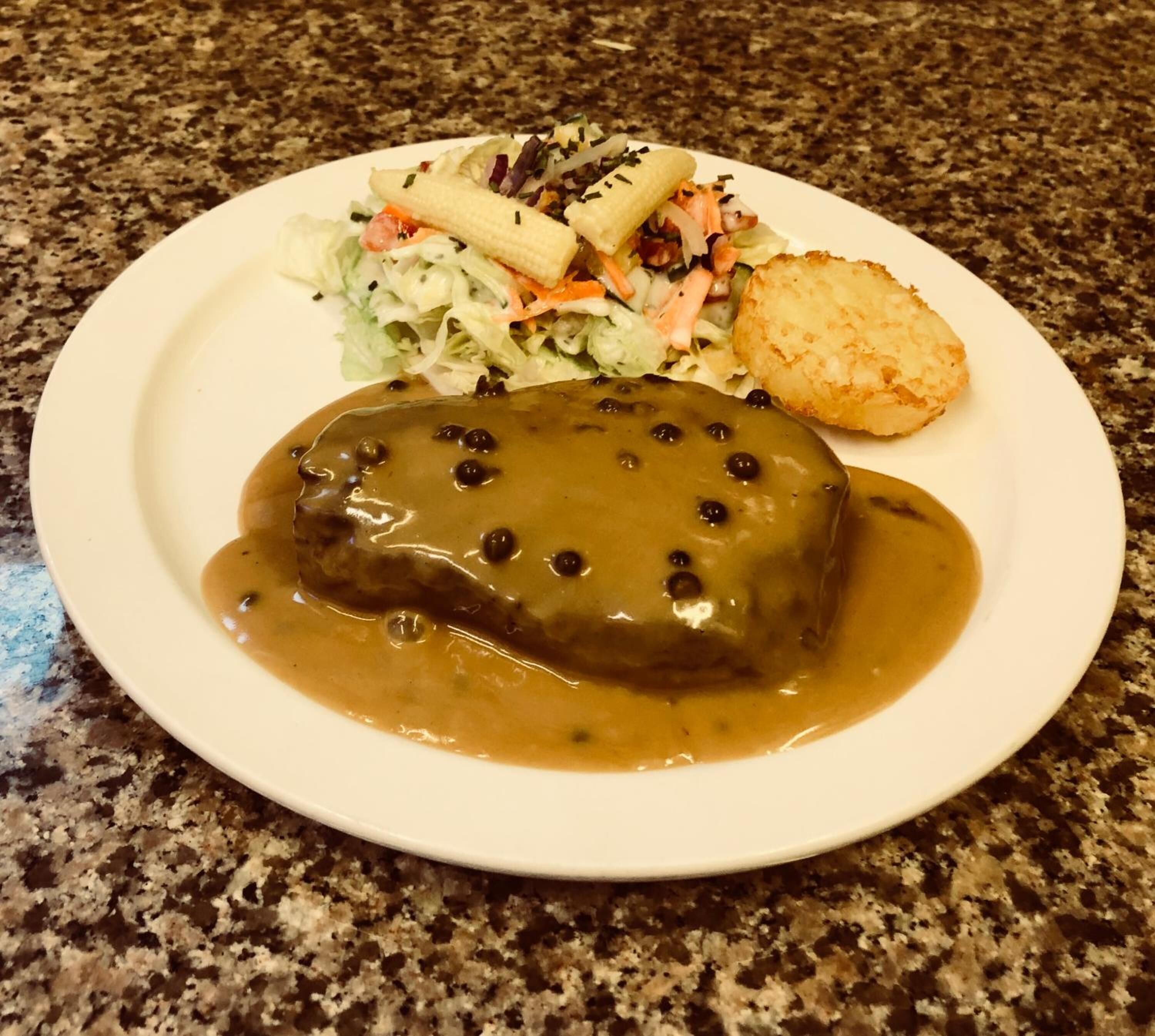 Un plato con un guiso de carne, una ensalada y algo frito.
