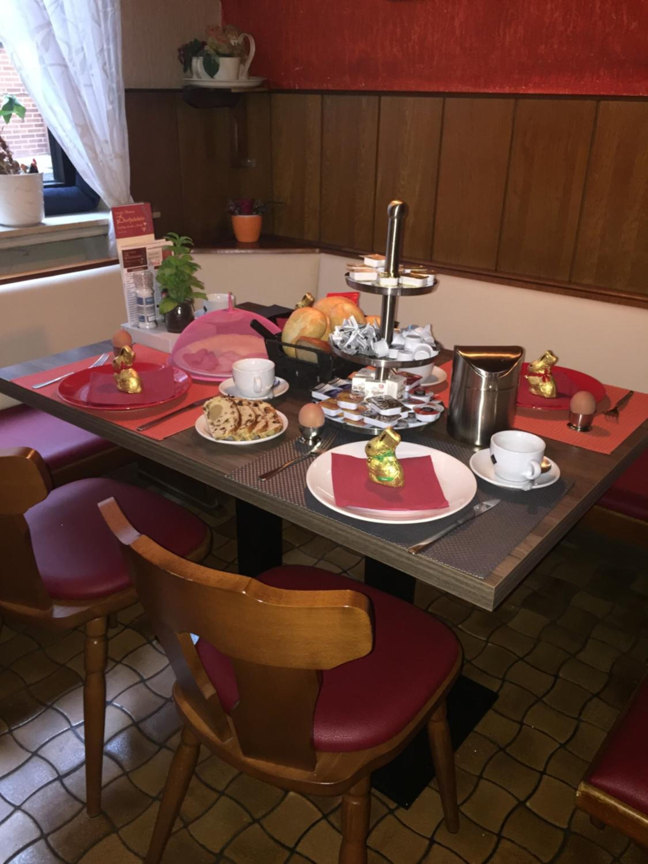 A breakfast table set with plates, cups, and a tiered tray of pastries.