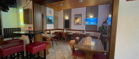 A restaurant with booths and tables, a tiled floor, and a sign above the entrance.