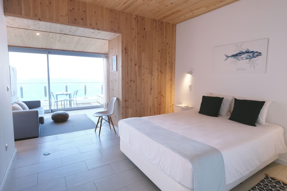 Een moderne slaapkamer met een groot bed, uitzicht en een houten plafond.