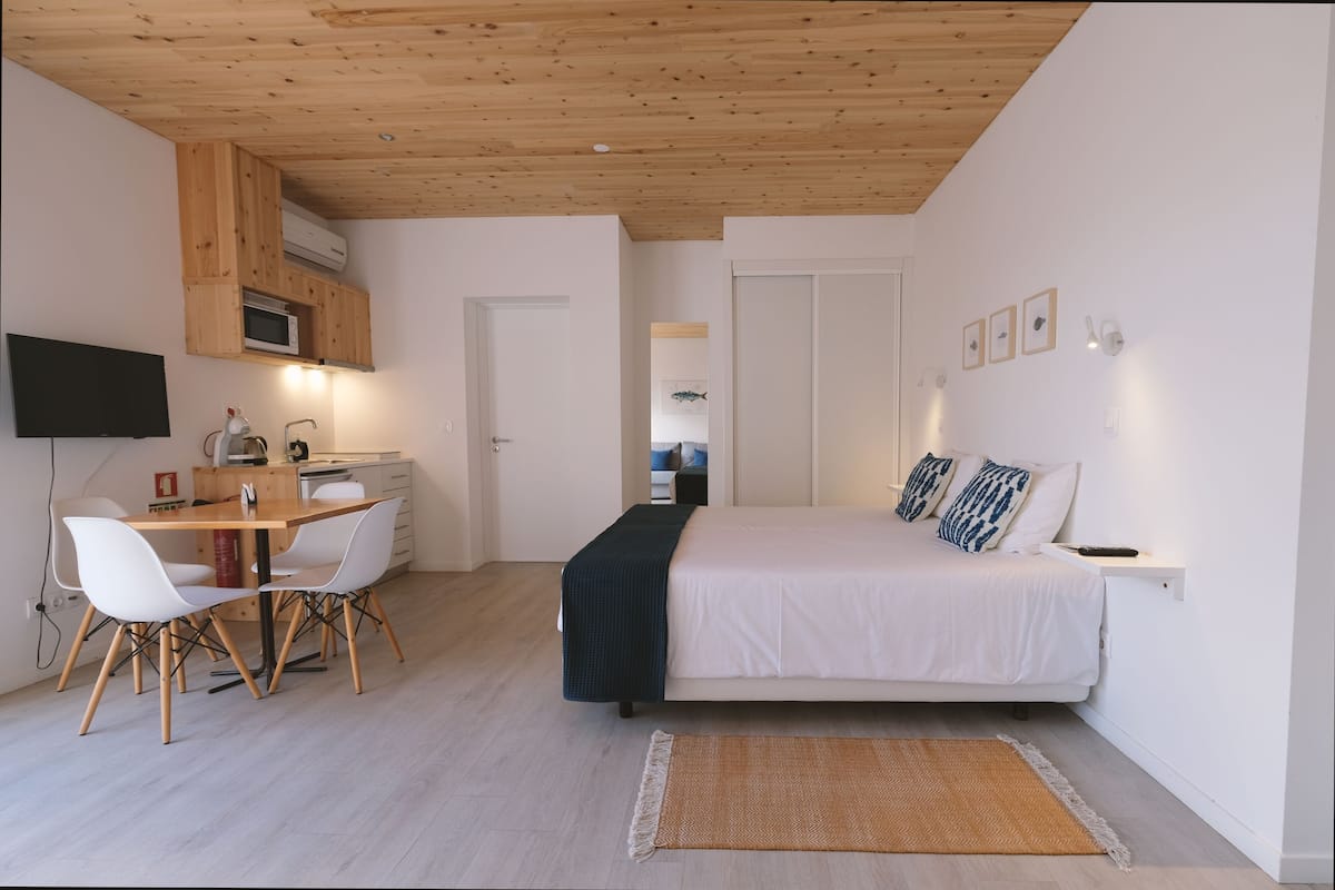 Een moderne slaapkamer met een bed, nachtkastje en een bureau met stoelen.