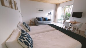 Un dormitorio con una cama grande, un sofá gris, un escritorio y un televisor.