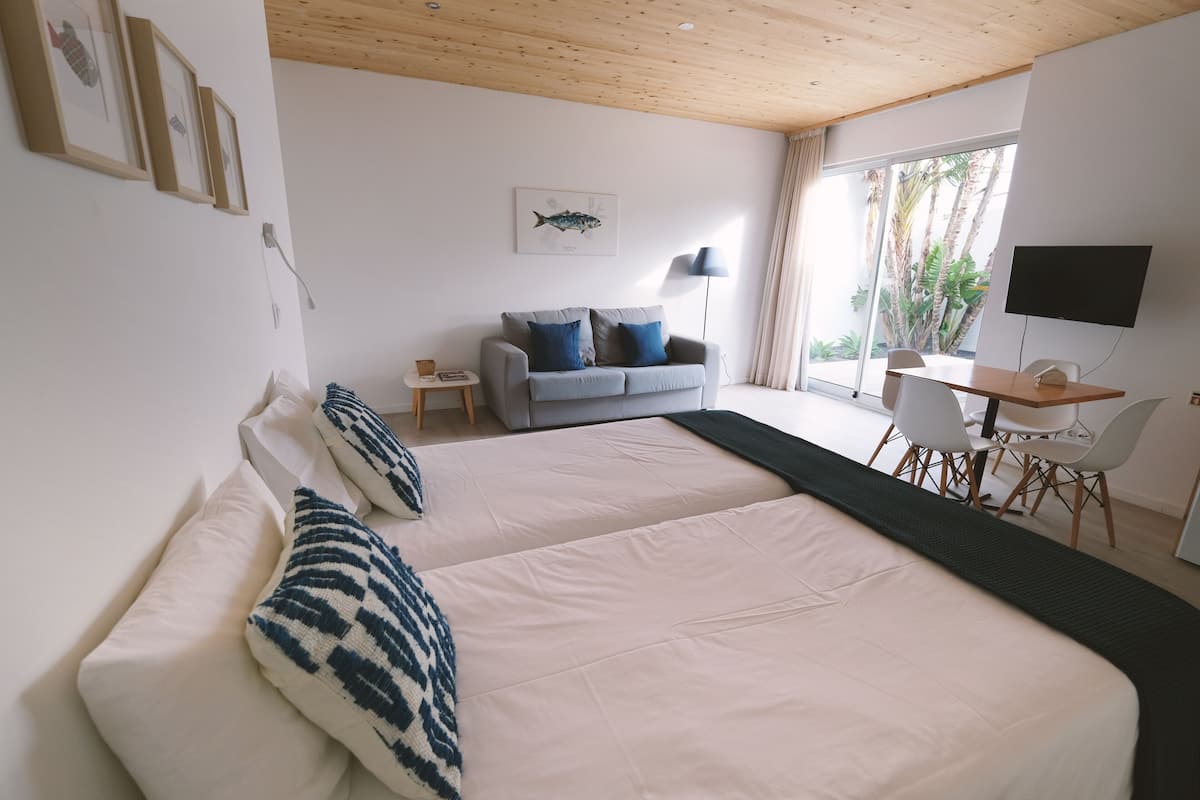 Een slaapkamer met een groot bed, een grijze bank, een bureau en een televisie.