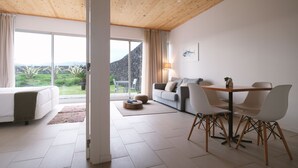 Una sala de estar moderna con techo de madera, un ventanal que ofrece vistas a zonas verdes y montañas, un comedor con mesa y sillas, y un sofá.