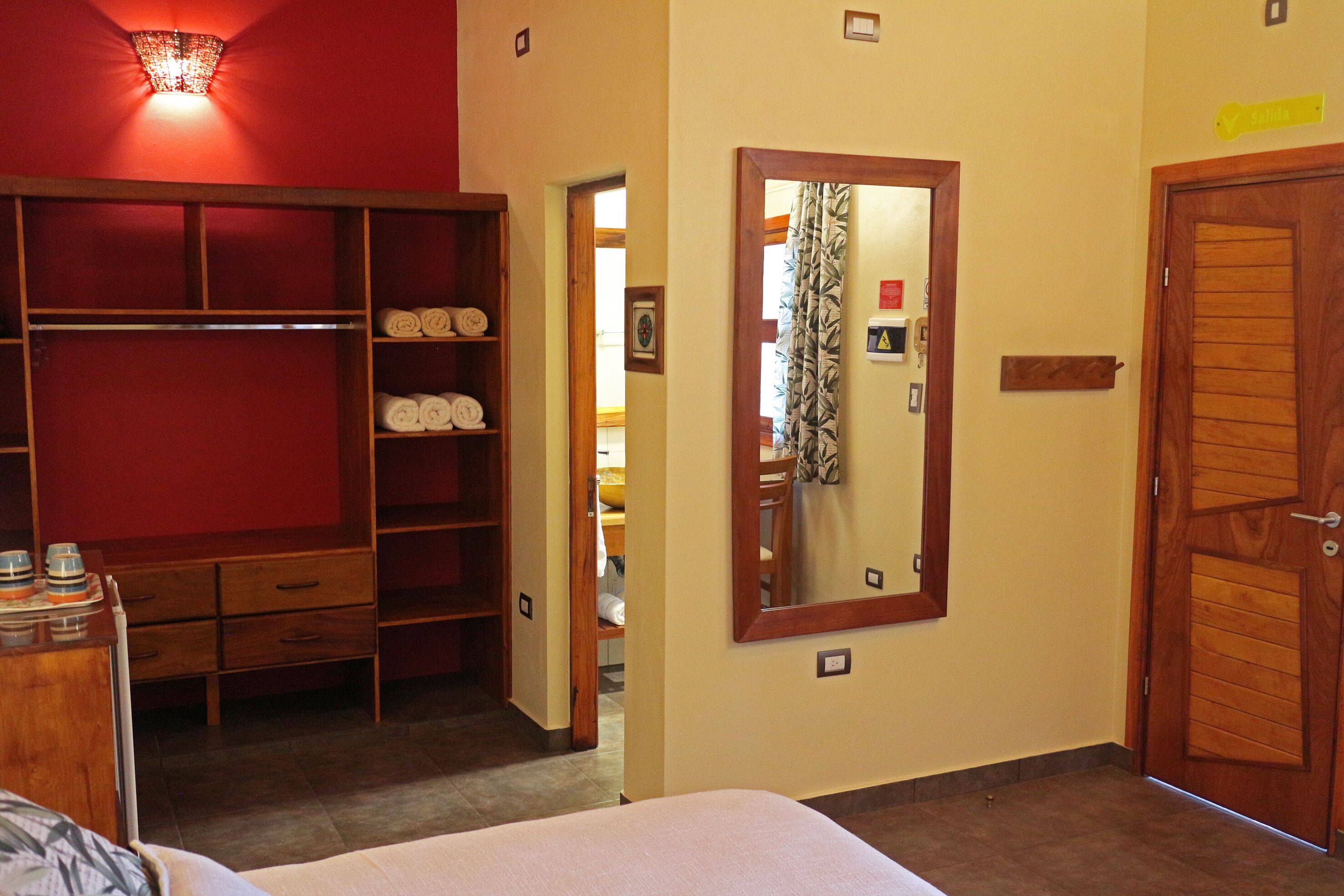 A hotel room with a bed, a wardrobe, a mirror, and a door.