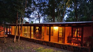 Eine rustikale Holzhütte mit steinernen Fundamenten, großen Glasscheiben und einer Holzterrasse.