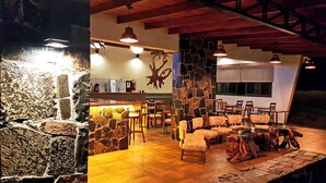 Ein Restaurant mit Steinwand, Holzbalkendecke und mehreren Tischen und Stühlen.