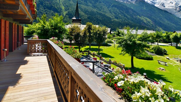A wooden balcony with a view of a mountain and a church. - Chalet Hotel le Castel (Chamonix-Mont-Blanc)