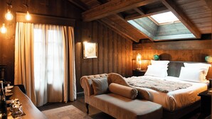 A cozy bedroom with a bed, a sofa, and a skylight. - Chalet Hotel le Castel (Chamonix-Mont-Blanc)