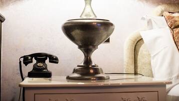 Una mesita de noche con un teléfono antiguo y una lámpara moderna.