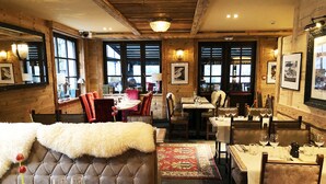 A cozy restaurant with wooden walls, plush seating, and a warm ambiance. - Chalet Hotel le Castel (Chamonix-Mont-Blanc)