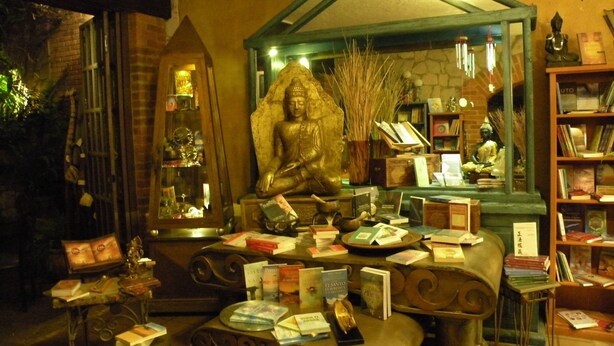A room with a Buddha statue, books, and a mirror reflecting the statue. - Casa Aurea (Morelia)