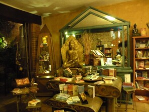 A room with a Buddha statue, books, and a mirror reflecting the statue. - Casa Aurea (Morelia)