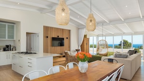 Una cocina moderna con una isla central, un comedor con mesa de madera y una sala de estar con sofá y una silla colgante.
