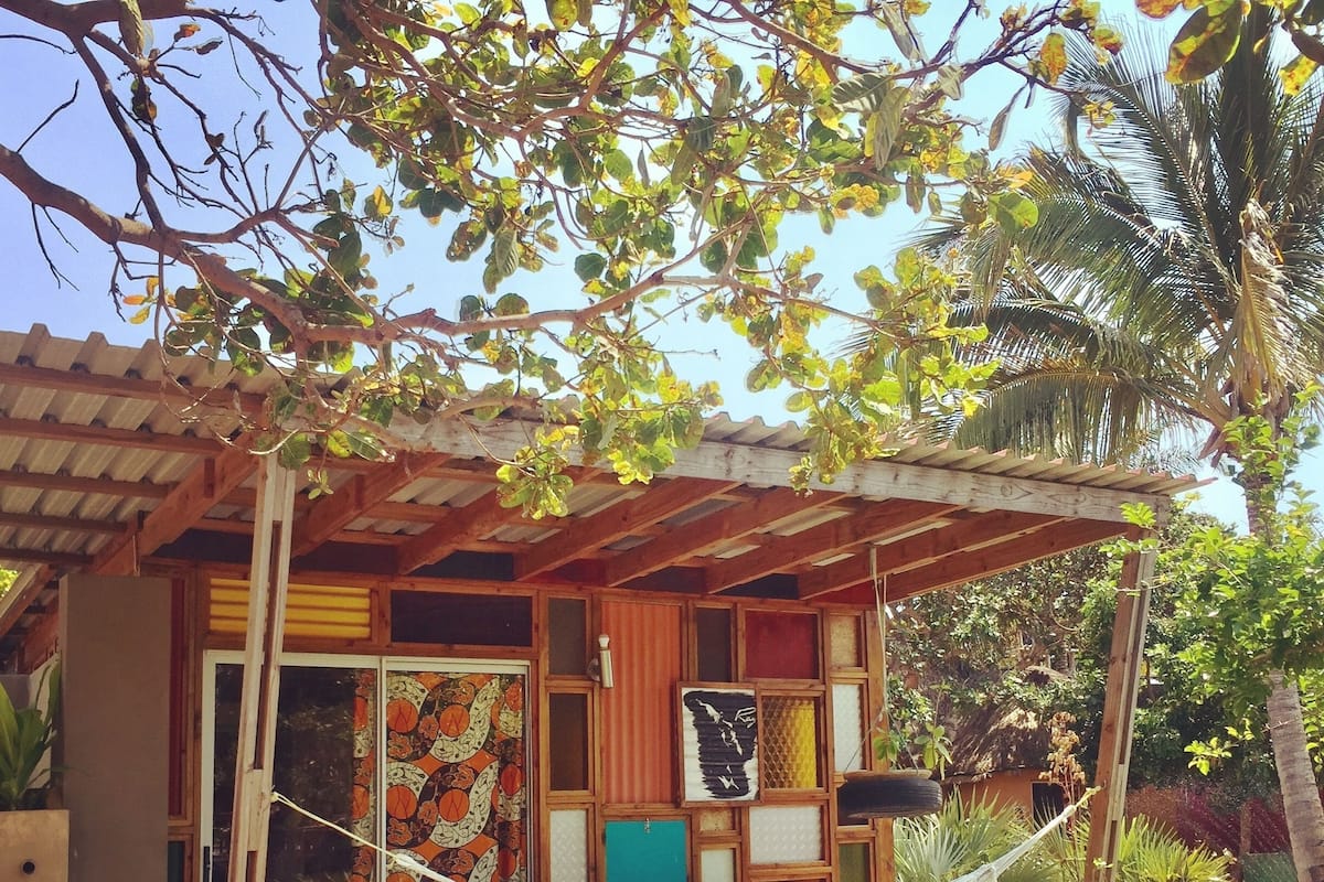 A wooden structure with a hammock, wooden deck, and a colorful wall.