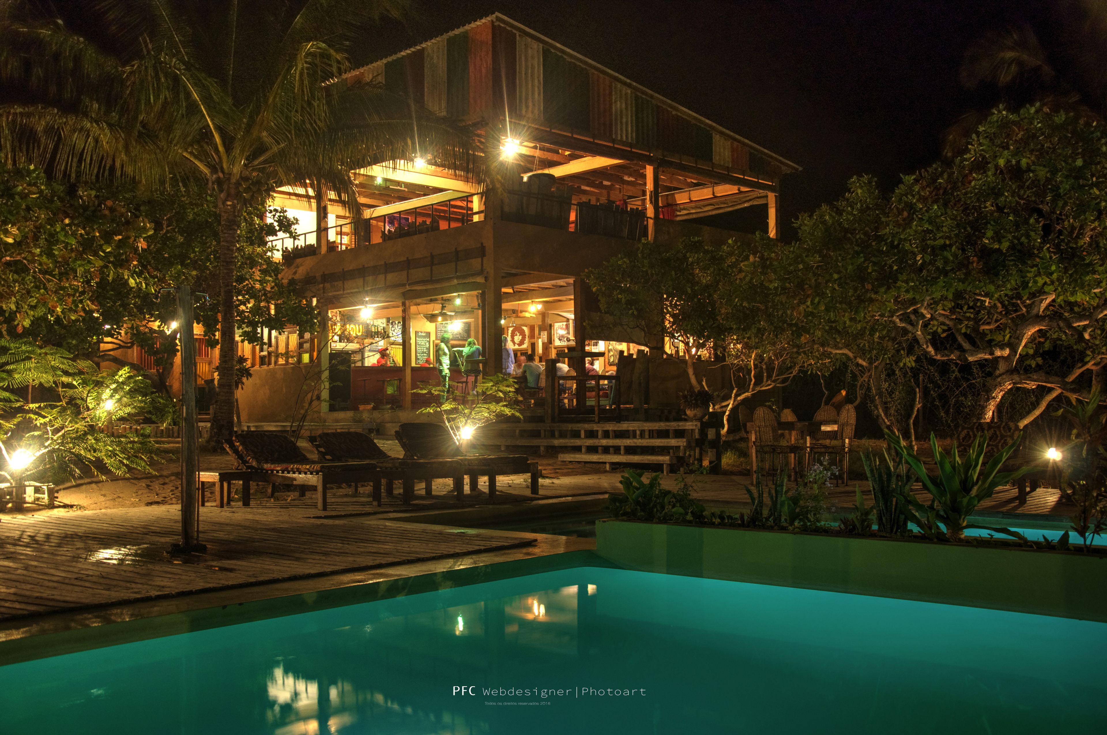A two-story building with a pool, outdoor seating, and a restaurant.
