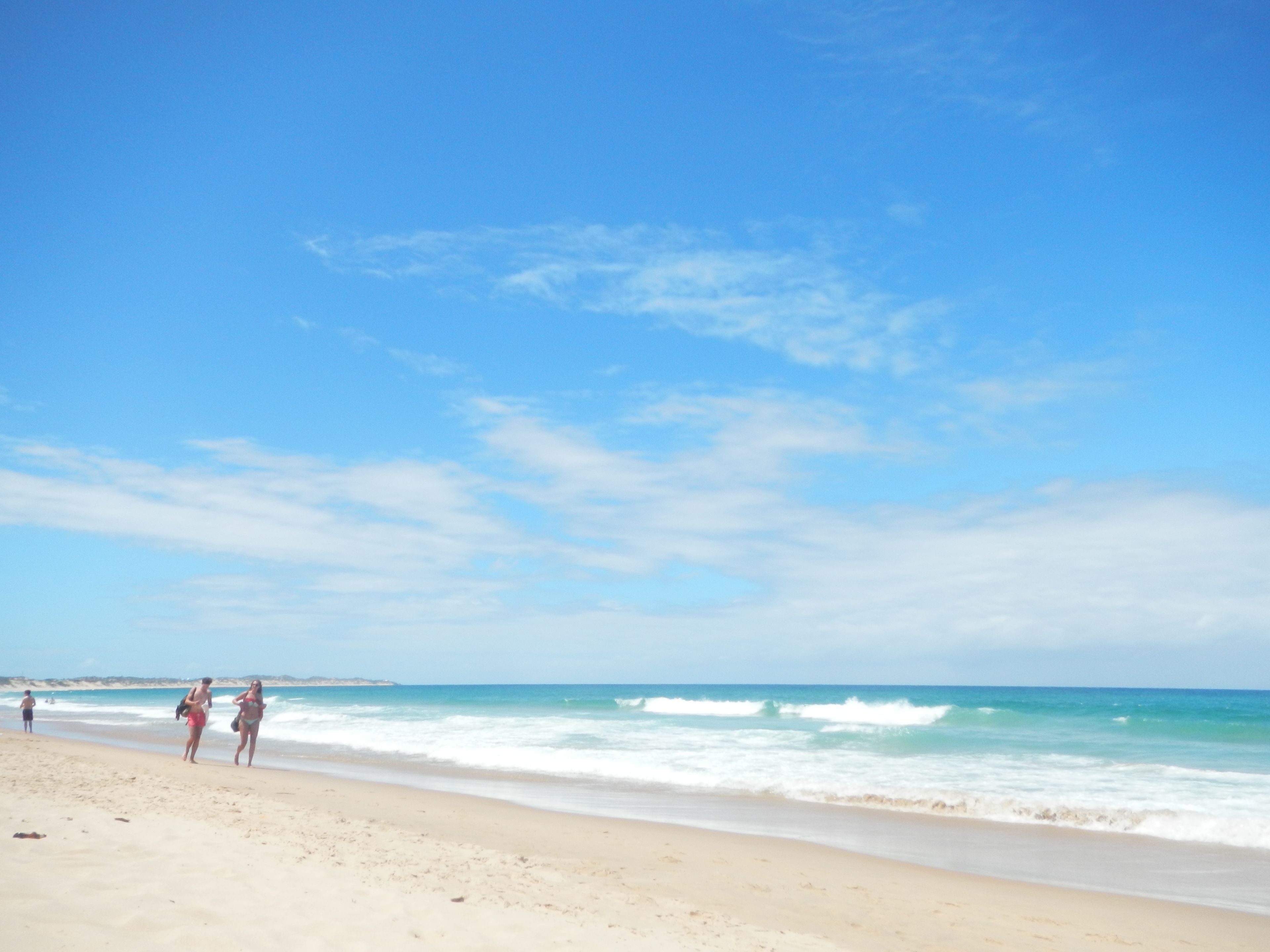 Una playa con cielo despejado y mar tranquilo.