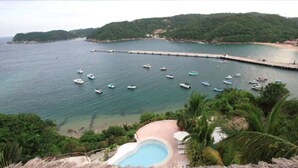 A coastal resort with a swimming pool, boats in the water, and a pier extending into the sea. - Hotel Playa Fandango (Santa María Huatulco)
