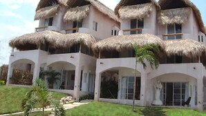 A multi-story building with thatched roofs and large windows. - Hotel Playa Fandango (Santa María Huatulco)