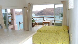 A room with a bed, a table, and a view of the sea. - Hotel Playa Fandango (Santa María Huatulco)