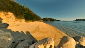 A beach with clear water, sandy shore, and large rocks. - Hotel Playa Fandango (Santa María Huatulco)