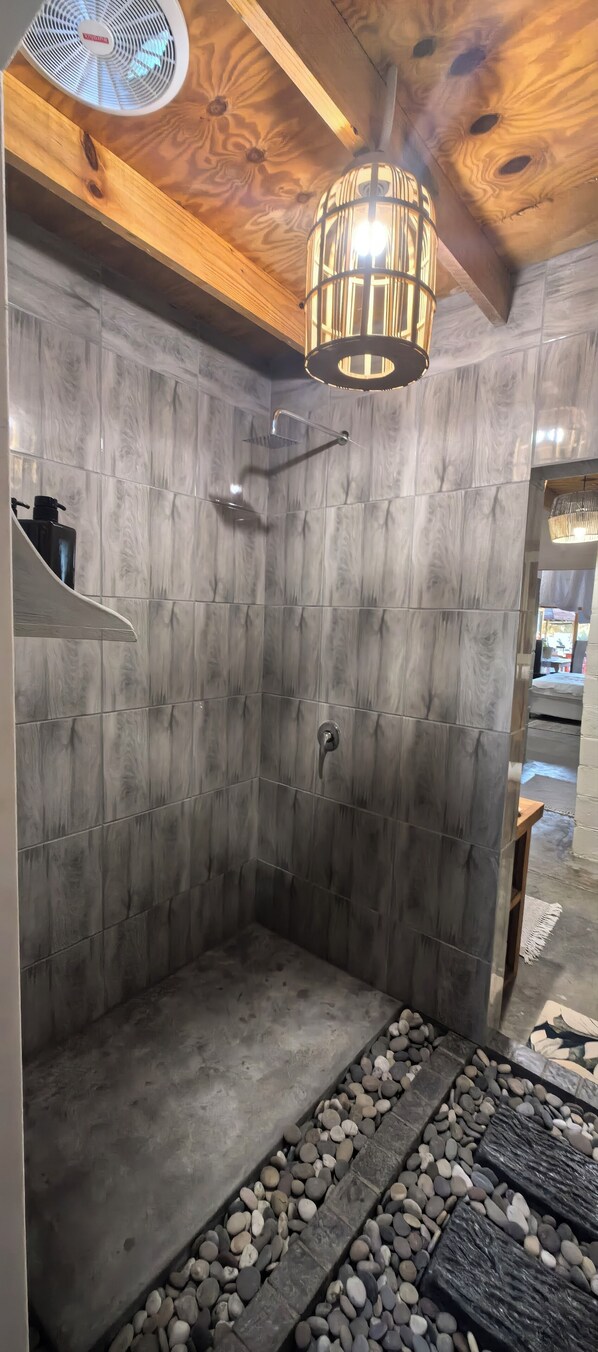 A shower with a wooden ceiling and a stone wall.