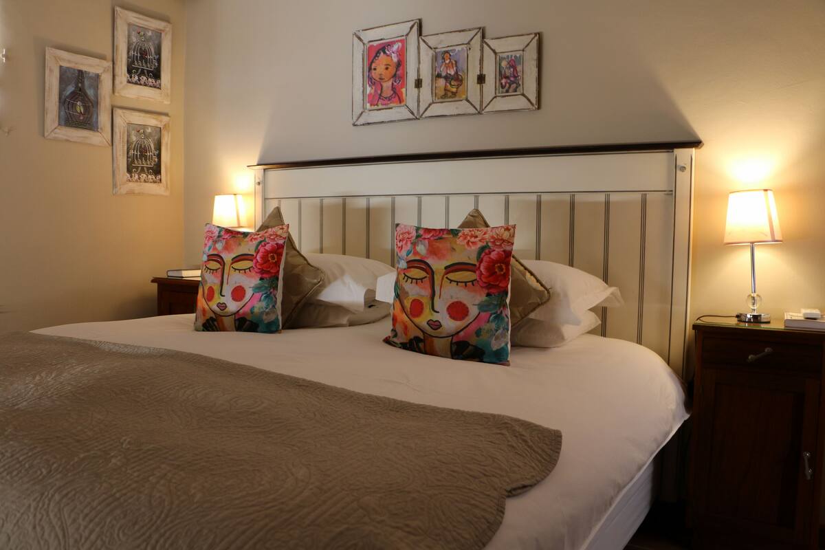 A neatly made bed with floral pillows, a wooden headboard, and bedside lamps.