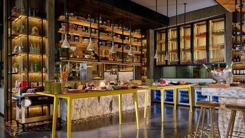 A modern bar area with a marble countertop, shelves with bottles, and hanging pendant lights.
