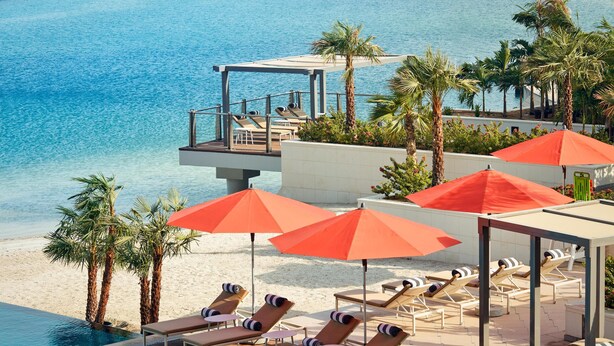 A poolside area with sun loungers and umbrellas, overlooking a beach and the sea. - Grand Hyatt Abu Dhabi Hotel & Residences (Abu Dhabi)