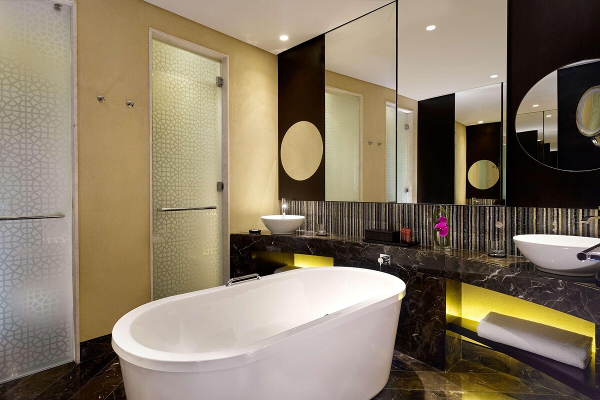 A modern bathroom with a freestanding bathtub, a large mirror, and a vanity with a sink.