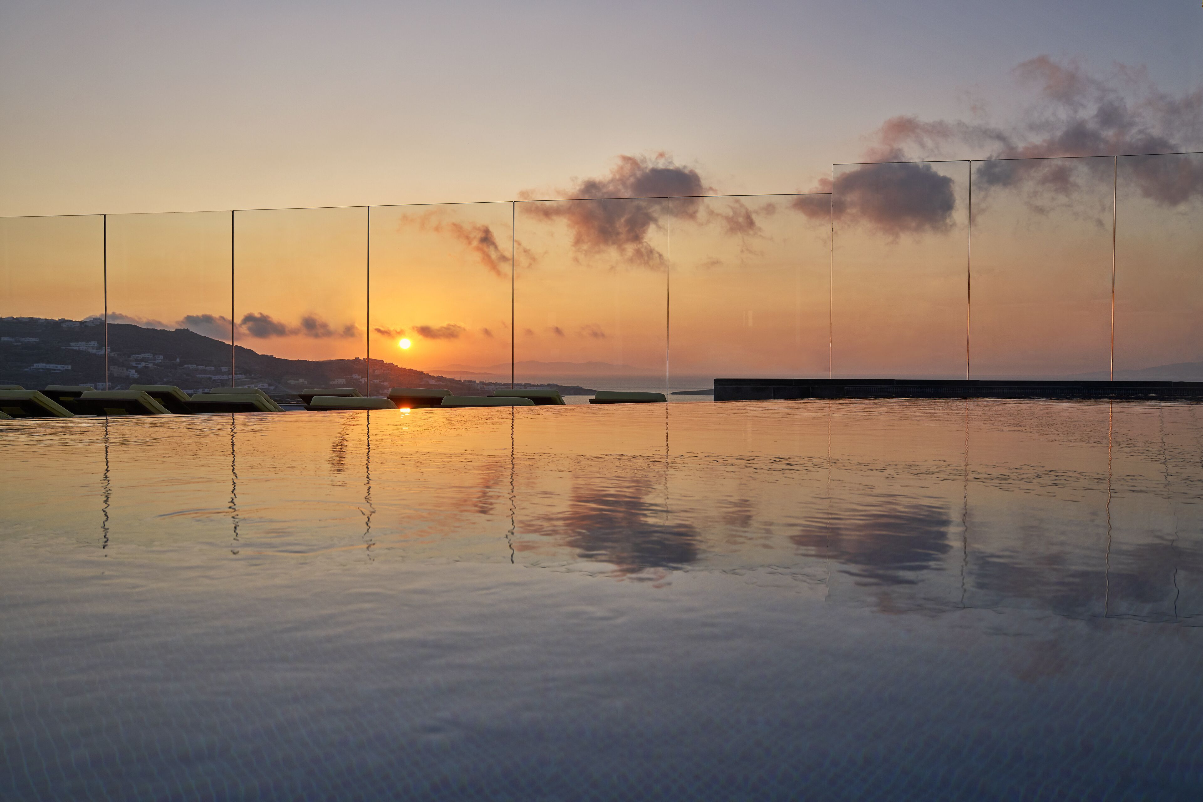 Un atardecer sobre un cuerpo de agua tranquilo, con una cadena montañosa distante.