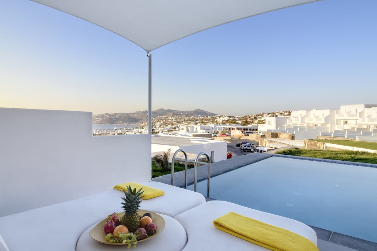 Ein Balkon mit Pool, weißen Möbeln und einer Obstschale.