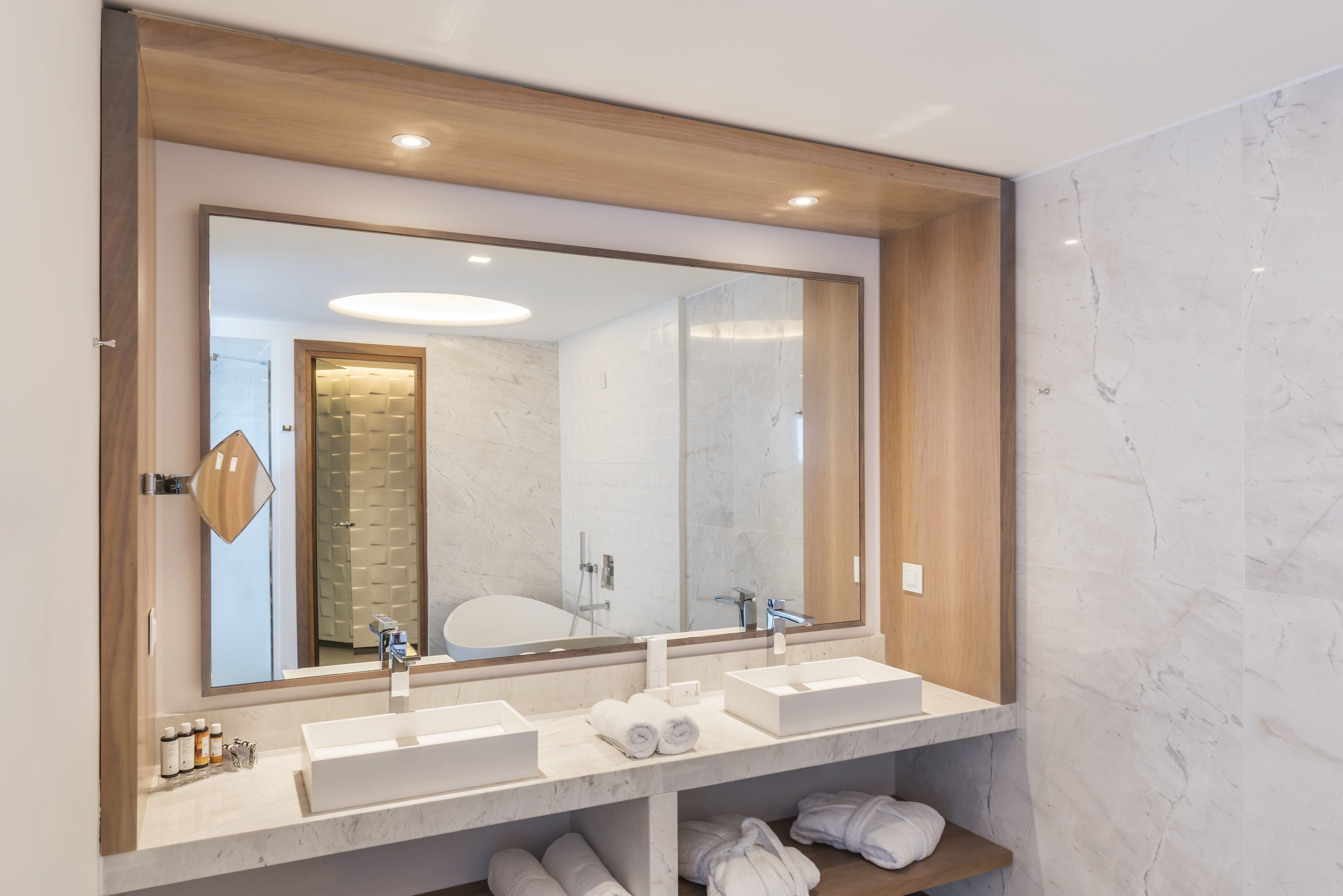 A modern bathroom with two sinks, a large mirror, and a wooden ceiling.