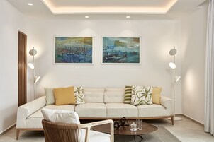 Una sala de estar moderna con un sofá color beige, dos cuadros y lámparas de pie.