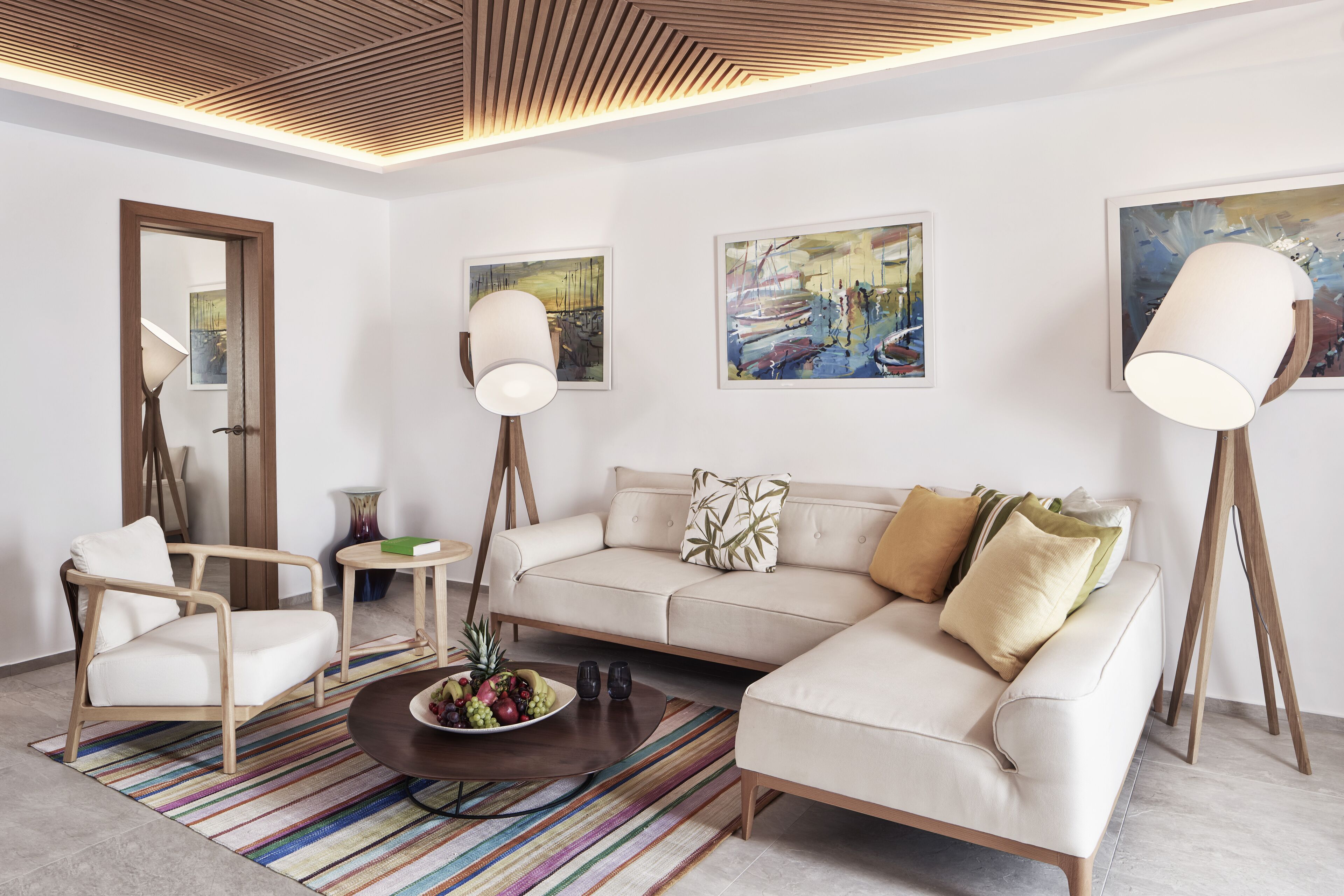 Una sala de estar moderna con un sofá, sillones, una mesita de centro con fruta y obras de arte en las paredes.