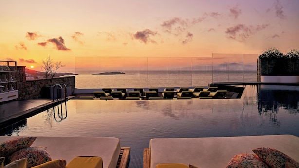 An infinity pool with lounge chairs and a sunset view. - Myconian Korali Relais & Chateaux (Mykonos)