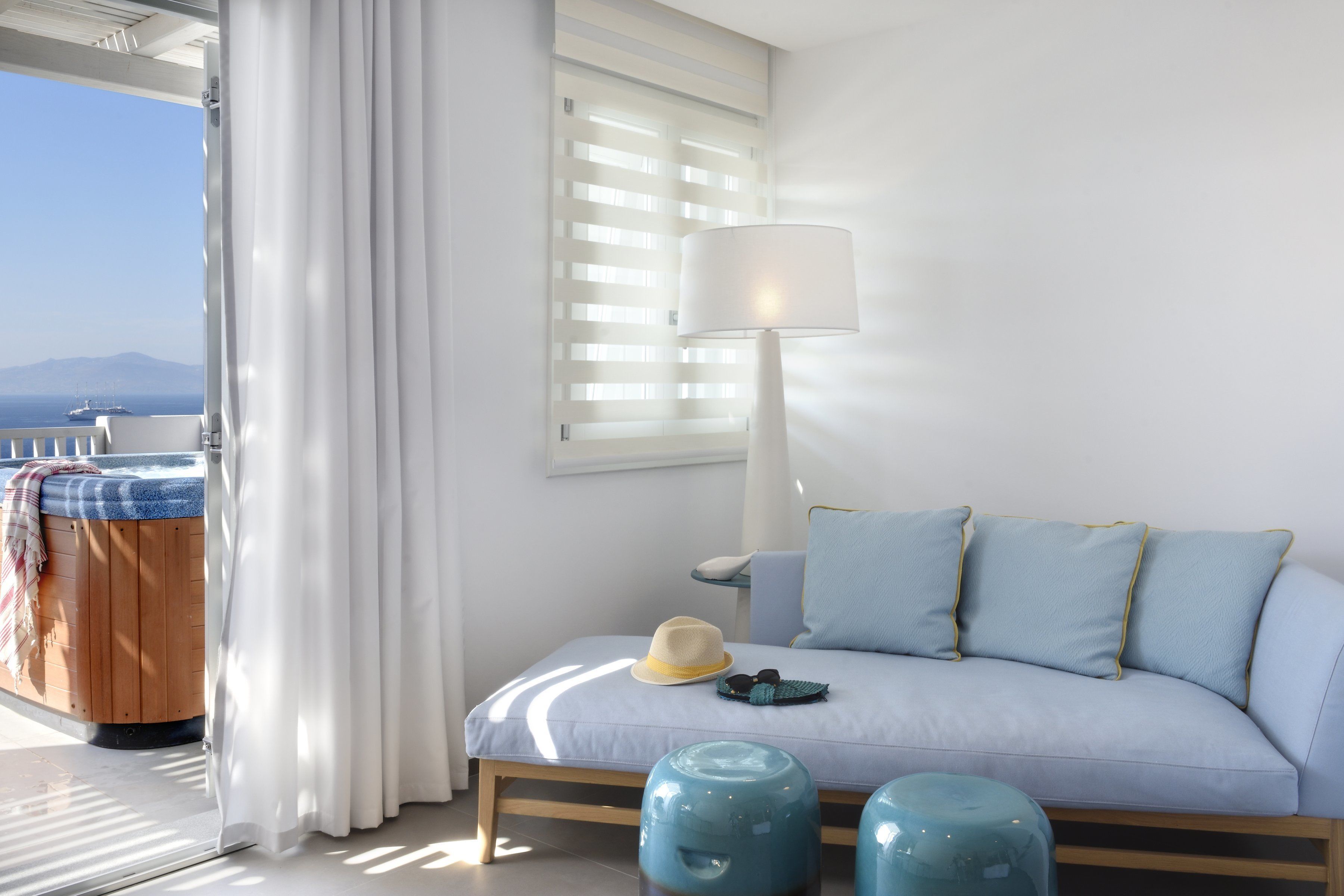 A room with a bed, a lamp, a hat, and a pair of sunglasses on the bed.