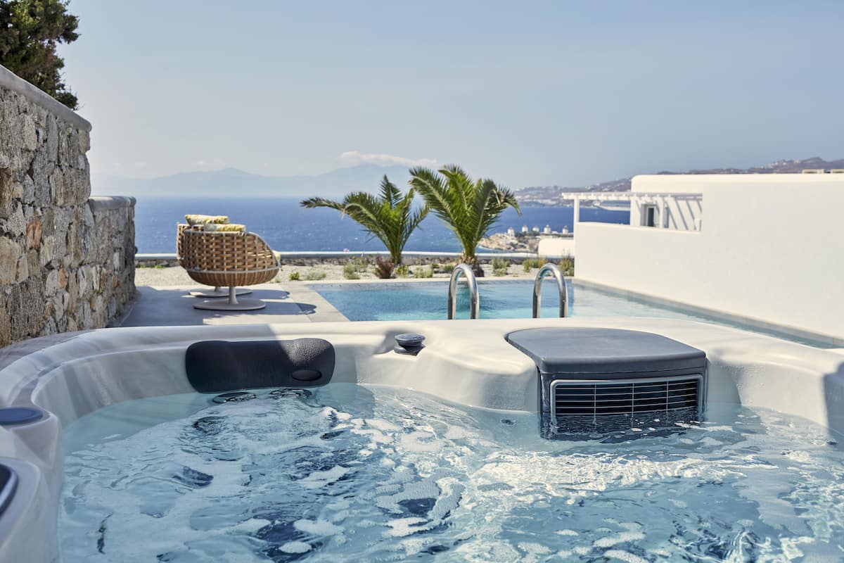 Ein Whirlpool mit Meerblick, eine Steinmauer und ein Korbsessel.