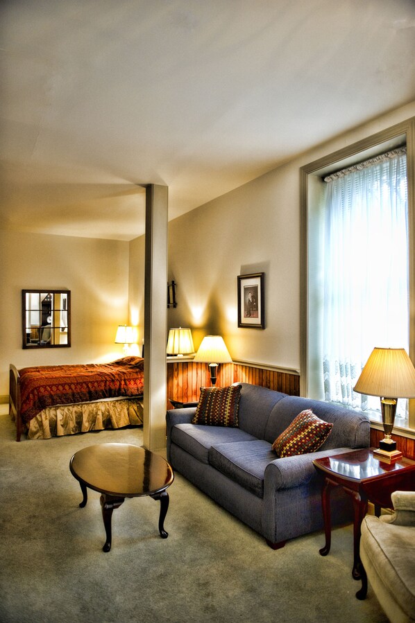 A hotel room with a bed, a sofa, a small table, and a window with curtains. - The Gables at Stirling Guest Hotel (Reading)